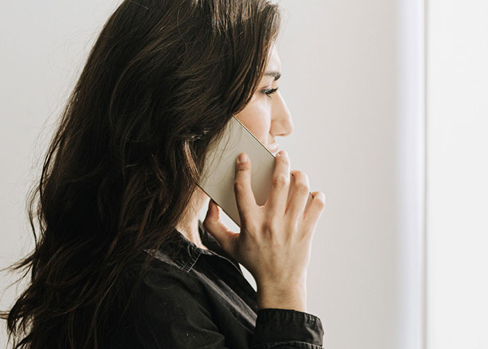 Woman with long dark hair in a black shirt talking on the phone, reflecting on refusing to pay medical bills for allergic reaction. Woman with long dark hair in a black shirt talking on the phone, reflecting on refusing to pay medical bills for allergic reaction.