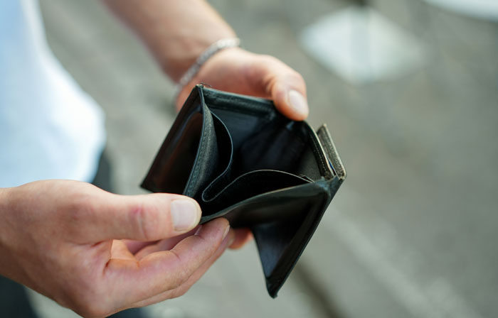 Person holding an empty black wallet, illustrating times strangers unsuccessfully attempted to mug them.