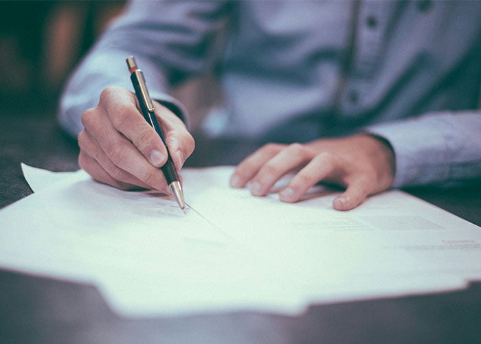 Person in charge writing notes with a pen on paper, illustrating infuriating things said by people in charge concept.