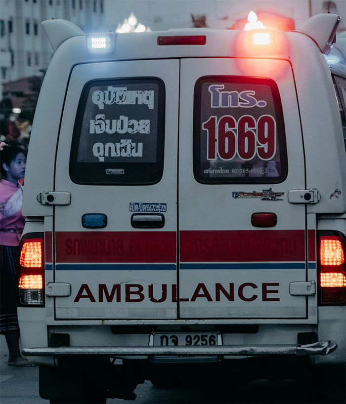 Rear view of an ambulance with flashing lights arriving, highlighting a severe case of attention seeking at an office. Rear view of an ambulance with flashing lights arriving, highlighting a severe case of attention seeking at an office.