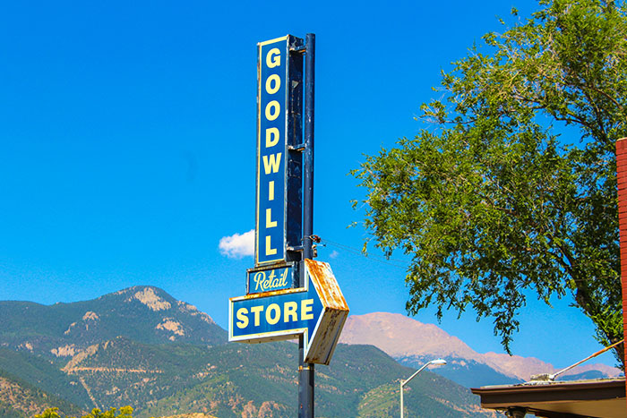 Vintage Goodwill retail store sign outdoors with mountains and clear blue sky, evoking gut feeling to leave now moments.