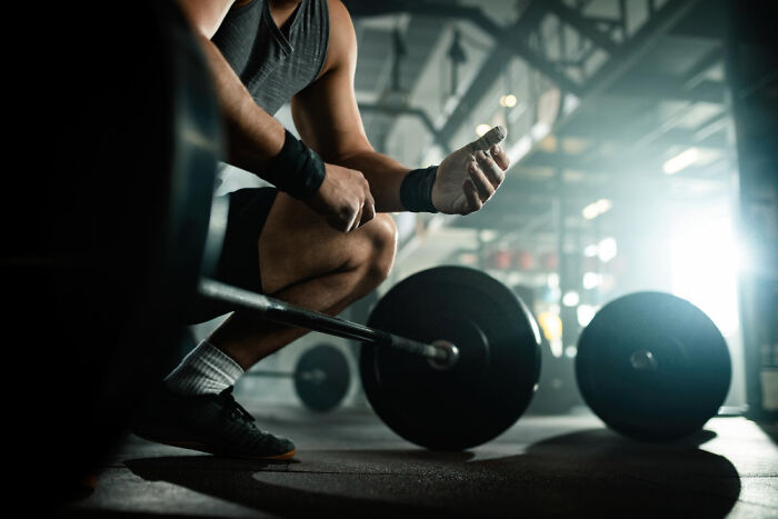 Man preparing to lift heavy barbell in gym, focused on strength training and workout routine with weightlifting equipment.