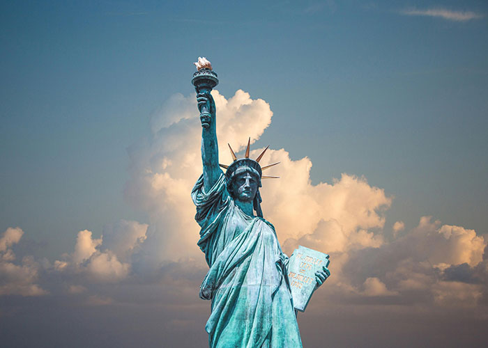 Statue of Liberty against a cloudy sky, symbolizing the best and worst things about living in home countries.