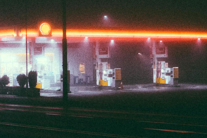 Foggy night at a deserted gas station, evoking a scary gut feeling to leave immediately in a tense atmosphere.