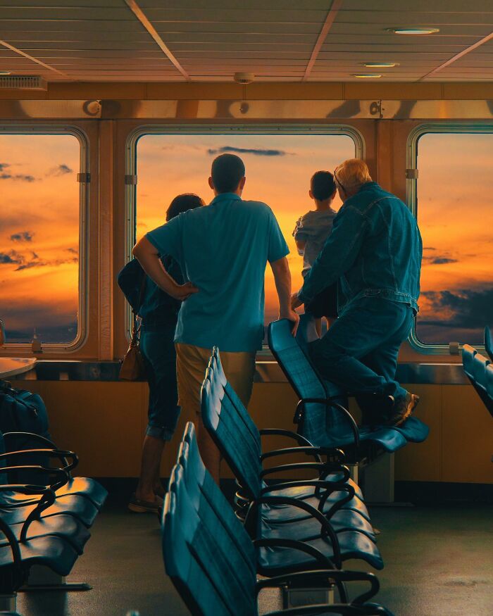 Family watching a surreal sunset through a ferry window, showcasing creative photo manipulations and surreal reality elements.