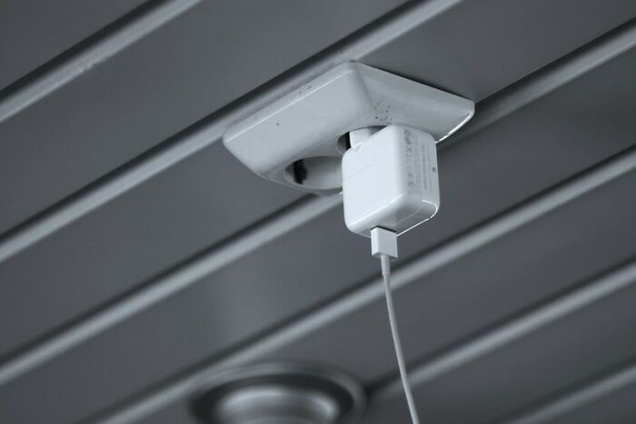 Close-up of an electrical adapter plugged into a ceiling outlet illustrating industry secrets behind closed doors.