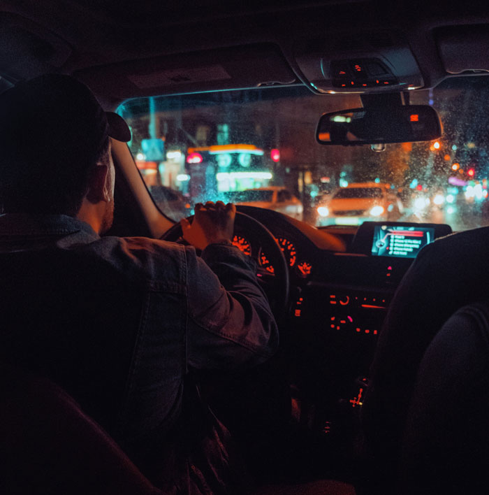 Man driving car at night on busy city street, illustrating secrets spouses keep until after marriage concept.