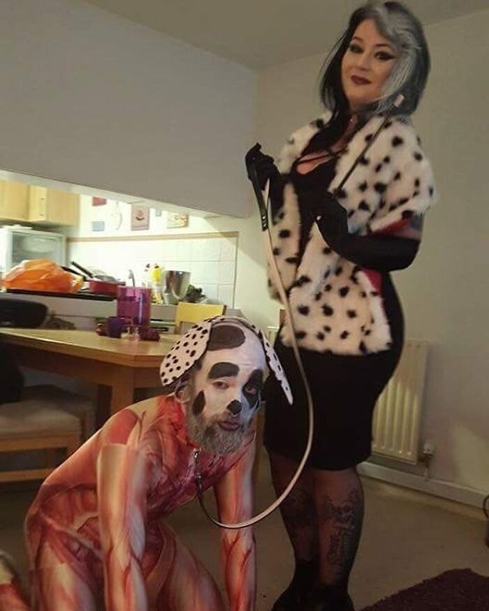 Person dressed in a dog costume on all fours with another dressed as Cruella, a cursed image for a weird break.