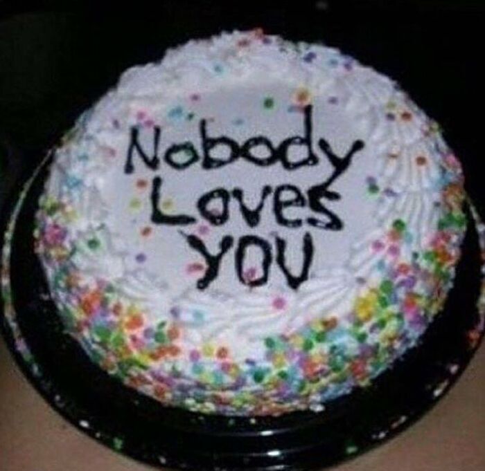 Round white frosted cake with colorful sprinkles and the cursed message nobody loves you, a cursed image for weird breaks.