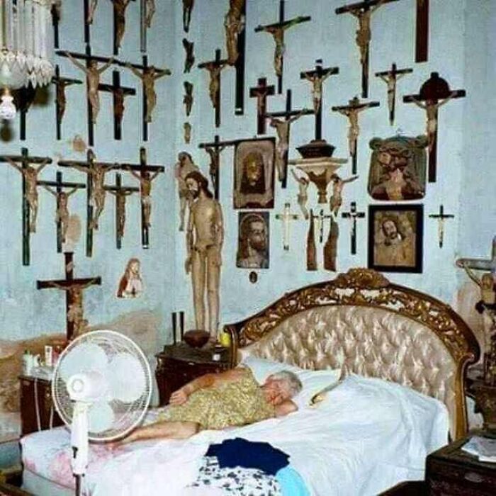 Elderly woman sleeping in a bedroom filled with numerous religious crucifix figures and portraits on the walls, cursed image.