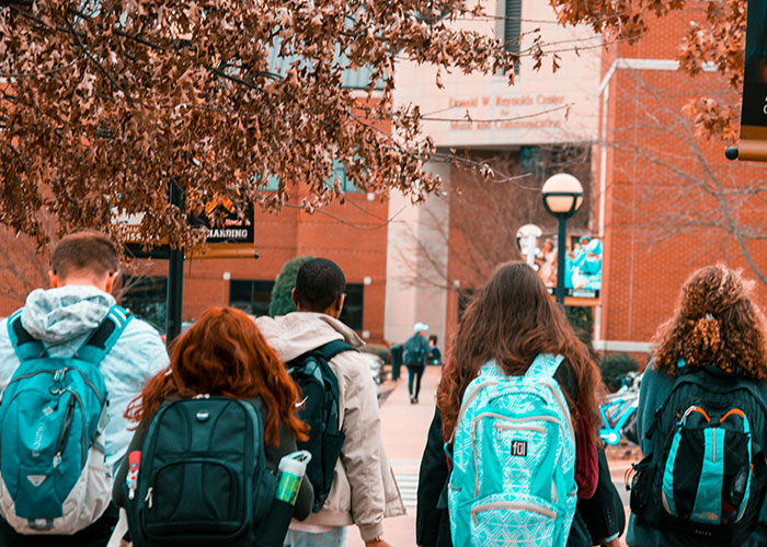 Group of students walking on campus with backpacks, illustrating the impact of student loan collections on borrowers. Group of students walking on campus with backpacks, illustrating the impact of student loan collections on borrowers.