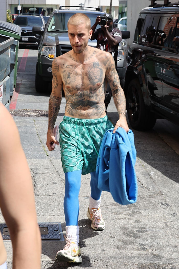 Justin Bieber shirtless walking in LA wearing green shorts and blue leggings while carrying a blue jacket outdoors. Justin Bieber shirtless walking in LA wearing green shorts and blue leggings while carrying a blue jacket outdoors.