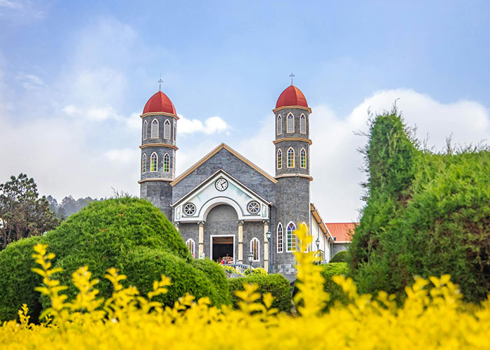 Historic church with red domes surrounded by lush greenery, illustrating the best and worst things about living in their home countries.