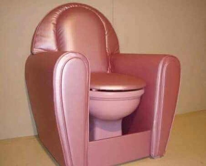 Pink upholstered armchair with an integrated pink toilet bowl, creating a cursed image with a weird and unsettling design.