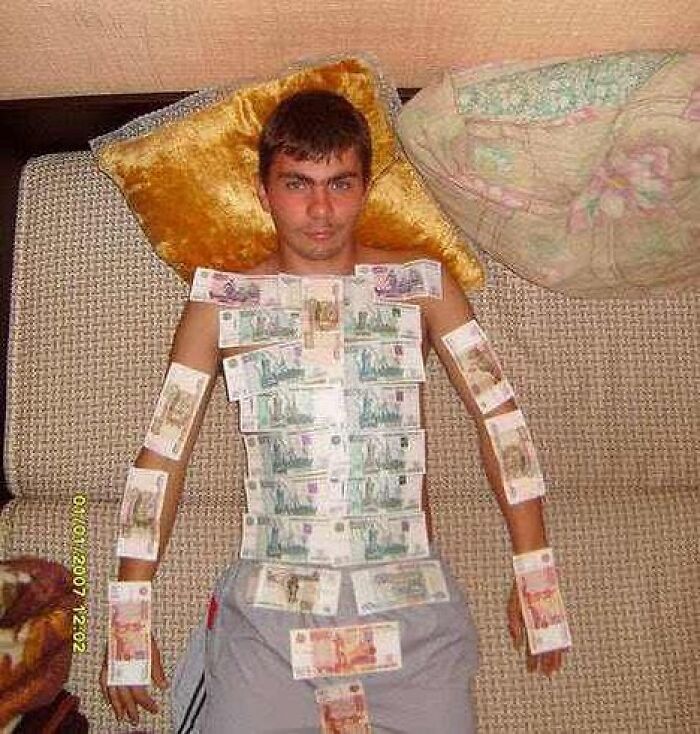 Man lying on couch with banknotes stuck all over his body in a bizarre and cursed image for a weird brain break
