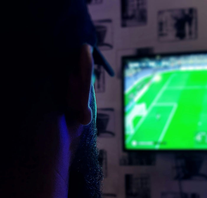 Man watching a video game screen in a dark room, illustrating secrets spouses may keep after marriage.