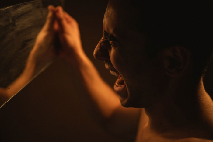 Man expressing intense emotion, symbolizing secrets spouses keep until after marriage in a dimly lit setting.