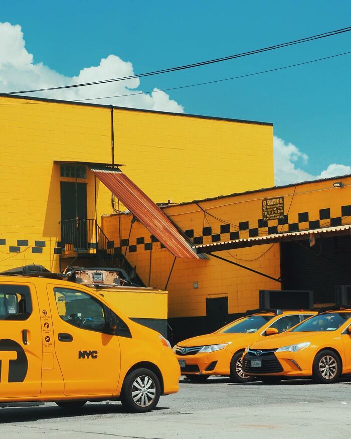 Yellow NYC taxis parked against a bright yellow building under a clear blue sky in a creative photo manipulation scene.