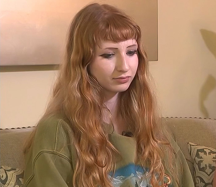 Teen girl with long red hair and green shirt sitting on a couch, involved in a debate over her trans prom date. Teen girl with long red hair and green shirt sitting on a couch, involved in a debate over her trans prom date.