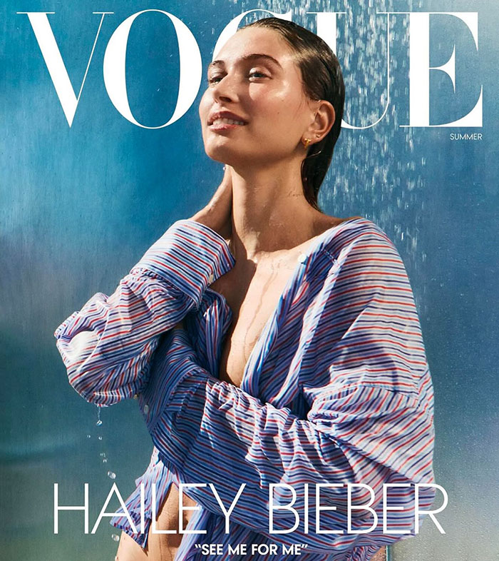 Hailey Bieber posing wet outdoors in a striped shirt for a Vogue Summer cover photo shoot. Hailey Bieber posing wet outdoors in a striped shirt for a Vogue Summer cover photo shoot.
