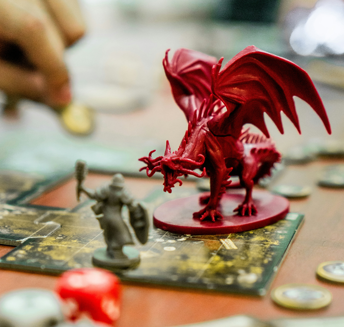 Close-up of a red dragon game piece and a warrior figurine on a board, illustrating intense fantasy gameplay and strategy. Close-up of a red dragon game piece and a warrior figurine on a board, illustrating intense fantasy gameplay and strategy.