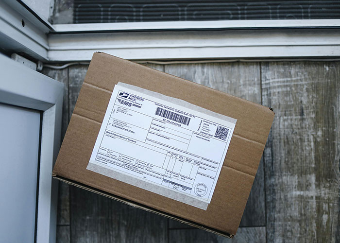 Brown cardboard package with a shipping label left on a doorstep, highlighting package theft by a neighbor incident. Brown cardboard package with a shipping label left on a doorstep, highlighting package theft by a neighbor incident.