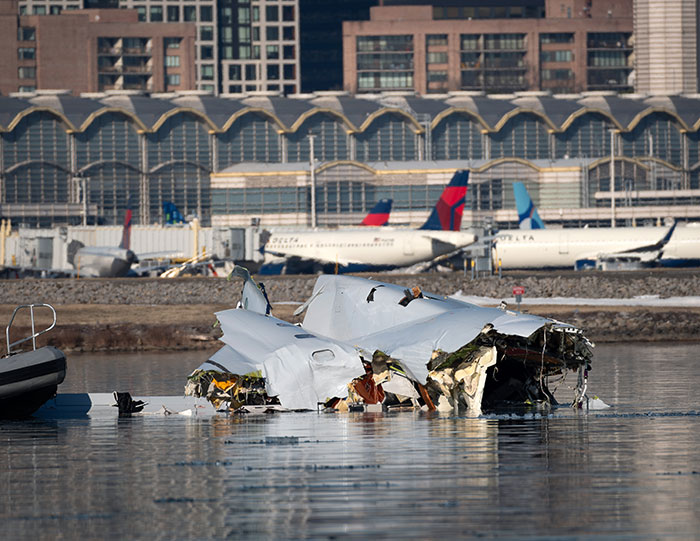 Wreckage of a plane crash partially submerged in water near an airport with Delta planes and buildings in the background Wreckage of a plane crash partially submerged in water near an airport with Delta planes and buildings in the background