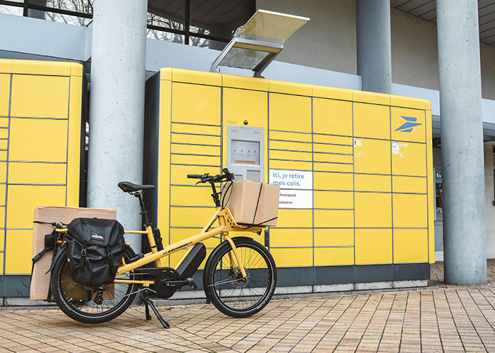 Yellow parcel locker with packages and a yellow bike in front, illustrating neighbor package theft and petty actions. Yellow parcel locker with packages and a yellow bike in front, illustrating neighbor package theft and petty actions.
