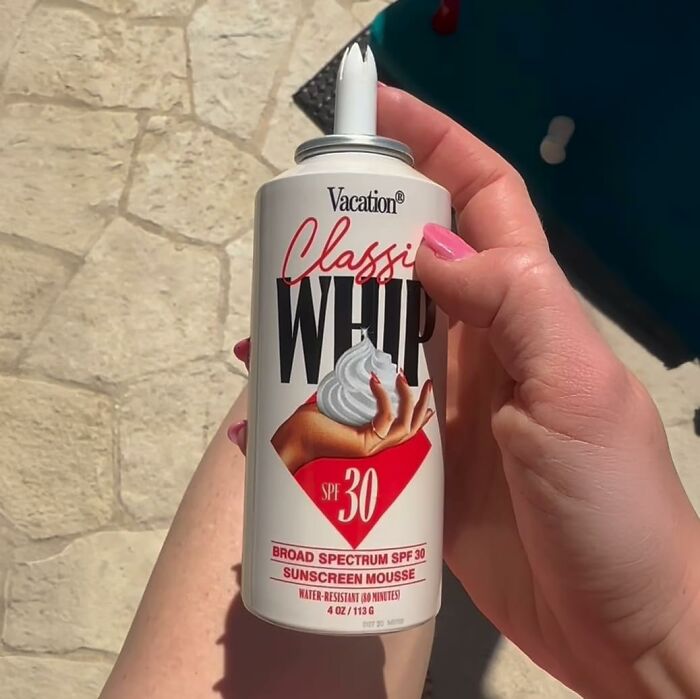 Hand holding Vacation Classic Whip SPF 30 broad spectrum sunscreen mousse for warm weather protection.