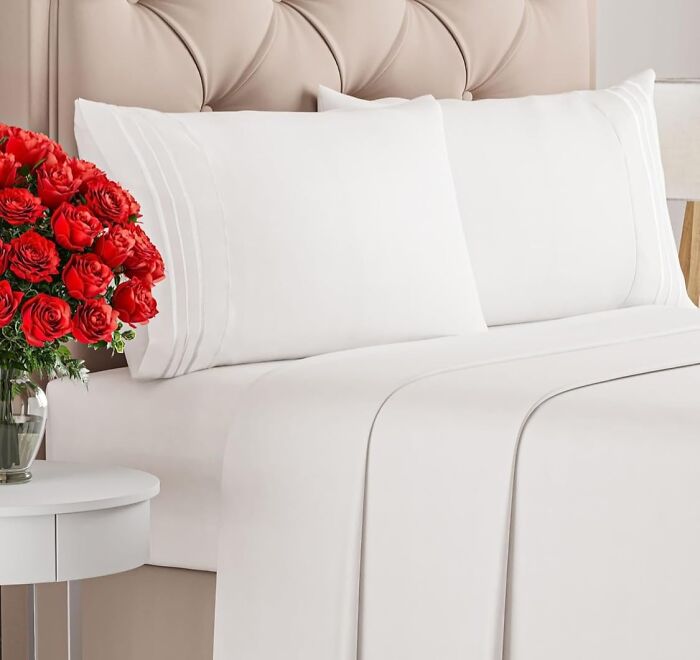 Soft white bedding set displayed on a bed with beige headboard and red roses, ideal for warm weather comfort.