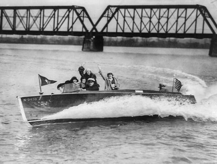 Vintage photo of people enjoying a boat ride on a river, showcasing life in America from 100 years ago.