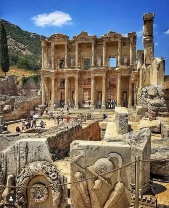 Ancient ruins with detailed stone carvings and large columns under a blue sky in an archaeology and architecture site.