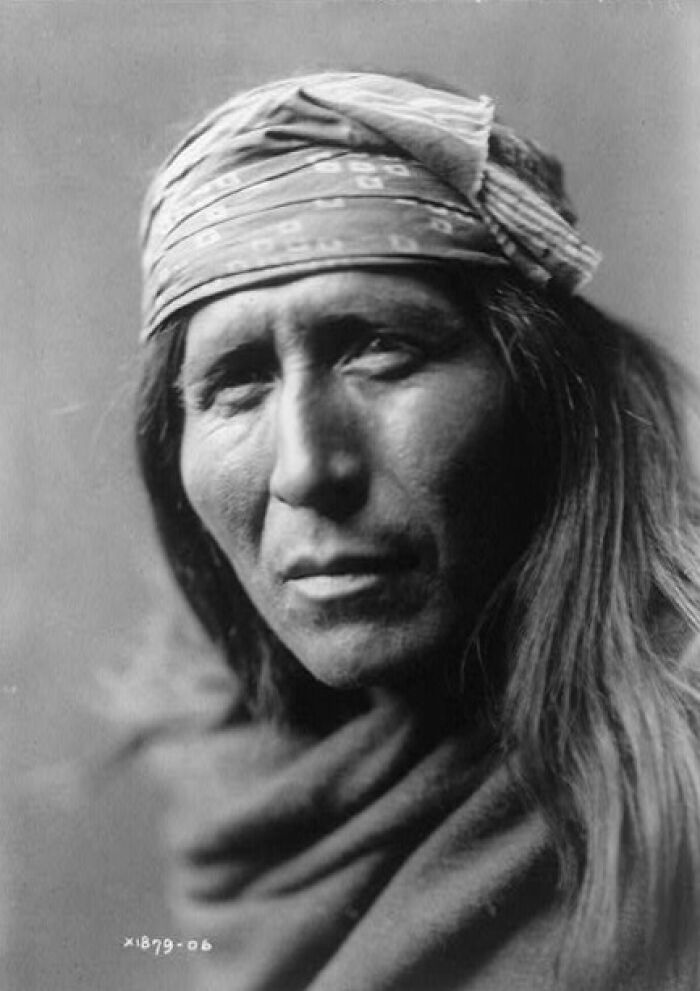 Portrait of Native American man from the 1900s wearing traditional bandana and heavy cloak, revealing powerful Native American life.