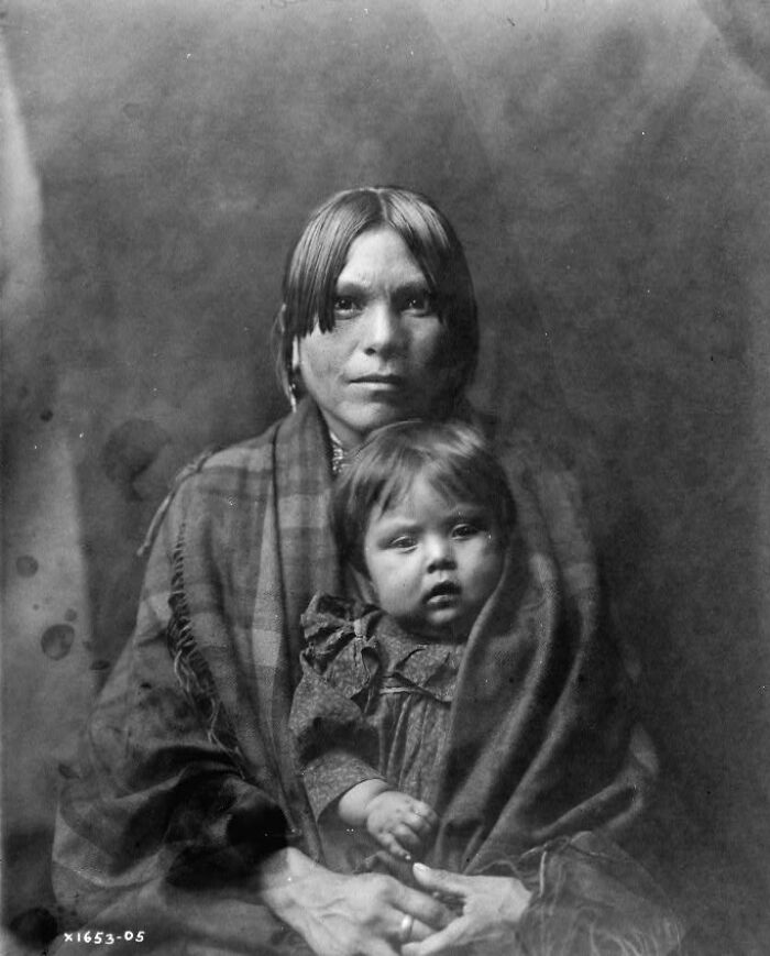 Native American woman and child wrapped in blankets, captured in a rare and powerful early 1900s photo.