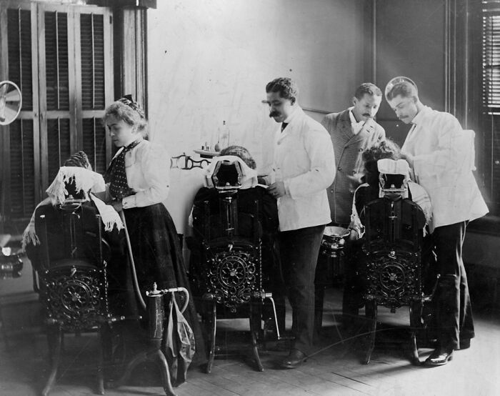 Barbers attending to clients in a vintage salon scene capturing African American life from the 1900 Paris Exposition.
