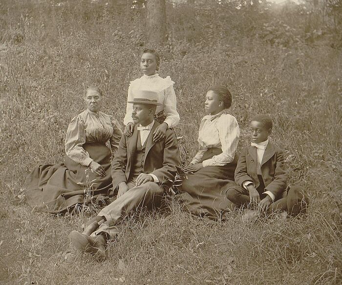 African American family dressed in early 1900s attire sitting outdoors, capturing a moment of African American life.