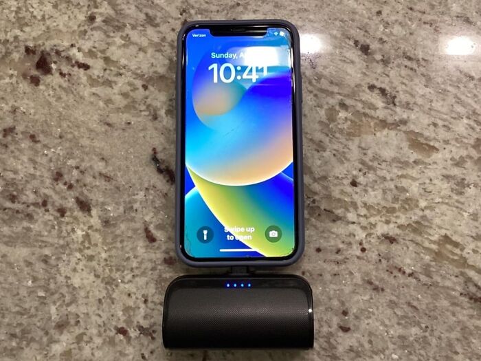 Smartphone and portable charger on a marble surface, essential for in-flight travel on a coach budget.