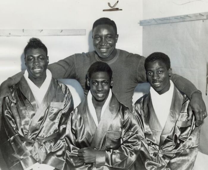 Four African Americans in uniform robes posing together and smiling in a black and white historical photo.