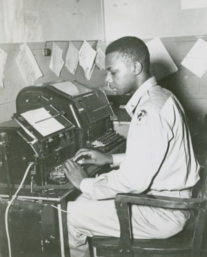 African American soldier in uniform operating a vintage military communication device in a historical office setting