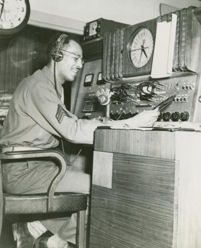 African American serviceman in uniform operating military communication equipment in a historical black and white photo.
