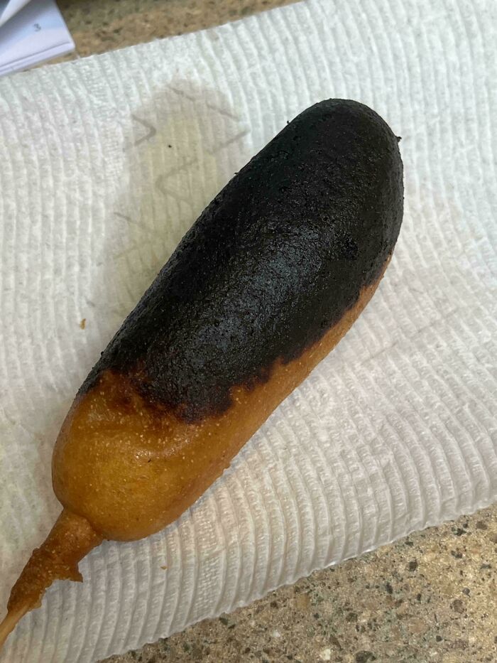 Burnt corn dog on a paper towel illustrating a cooking fail and accident from humorous kitchen mistakes.