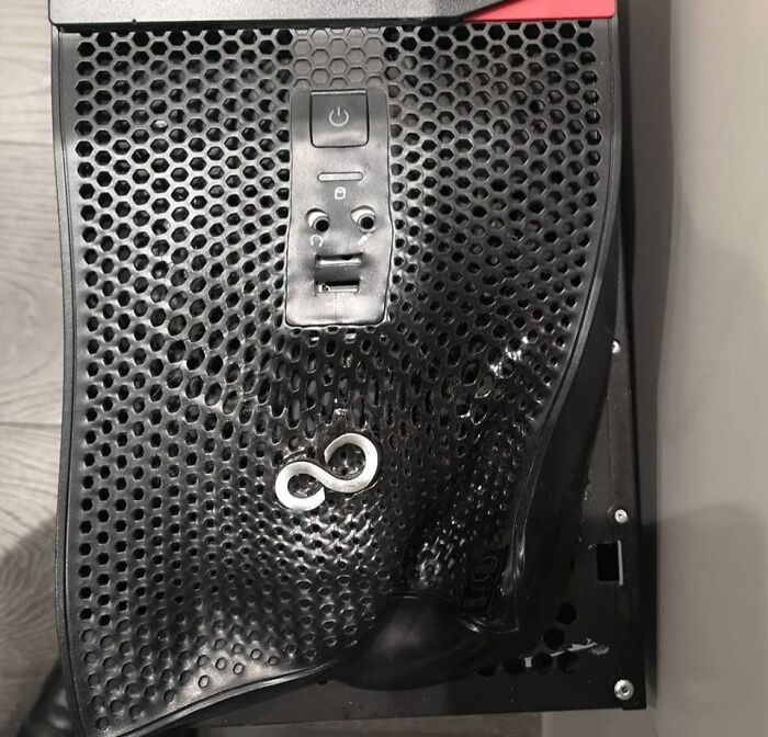 Black computer case with a melted front panel creating a face-like illusion, illustrating technology disasters and malfunctions.