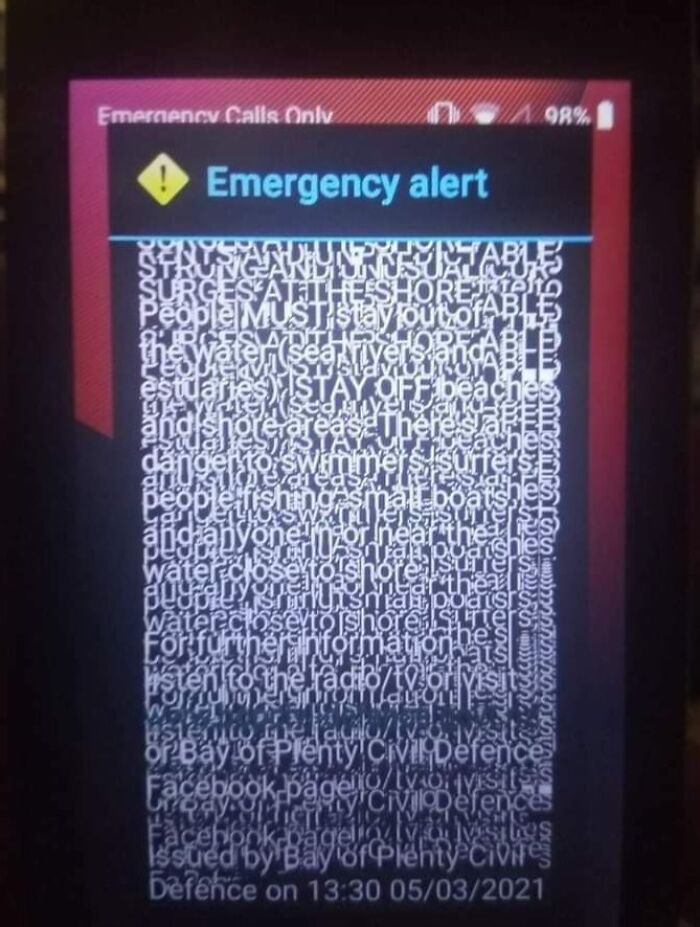 Emergency alert with overlapping scrambled text on smartphone screen, illustrating a technology disaster and system failure.