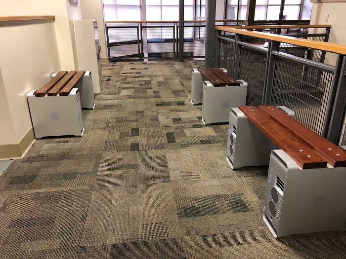 Benches made from recycled computer towers with wooden seats in an indoor hallway, showcasing technology disasters design.
