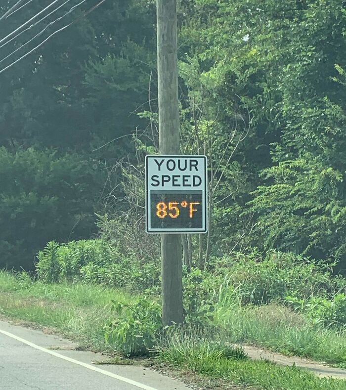 Radar speed sign incorrectly displaying temperature as speed on a rural road, illustrating technology disasters.