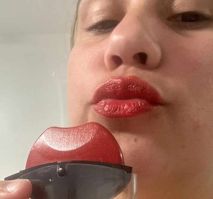 Close-up of a person with red lipstick holding a red lip-shaped compact, highlighting hilarious finds under $10.