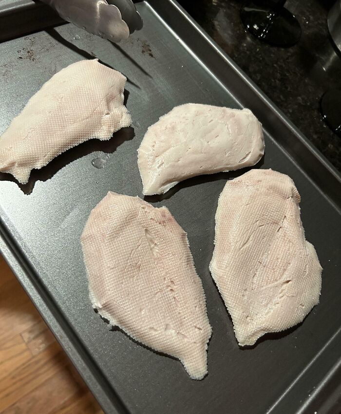 Raw, tough-looking cooking fail with strange pale meat pieces on a baking tray, highlighting painful cooking fails.