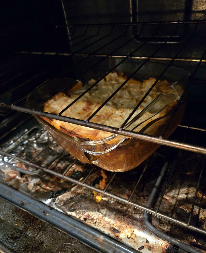 Broken glass baking dish inside an oven with a c*****d edge, illustrating a cooking fail and kitchen accident.