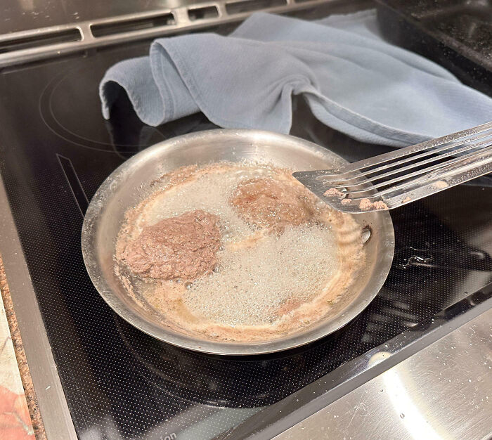 Cooking fail with overcooked and unevenly cooked patties frying in a pan on an electric stove.