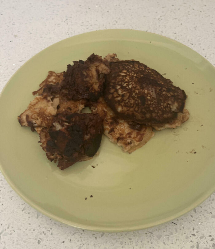 Burnt and misshapen pancakes on a green plate illustrating cooking fails and kitchen accidents.